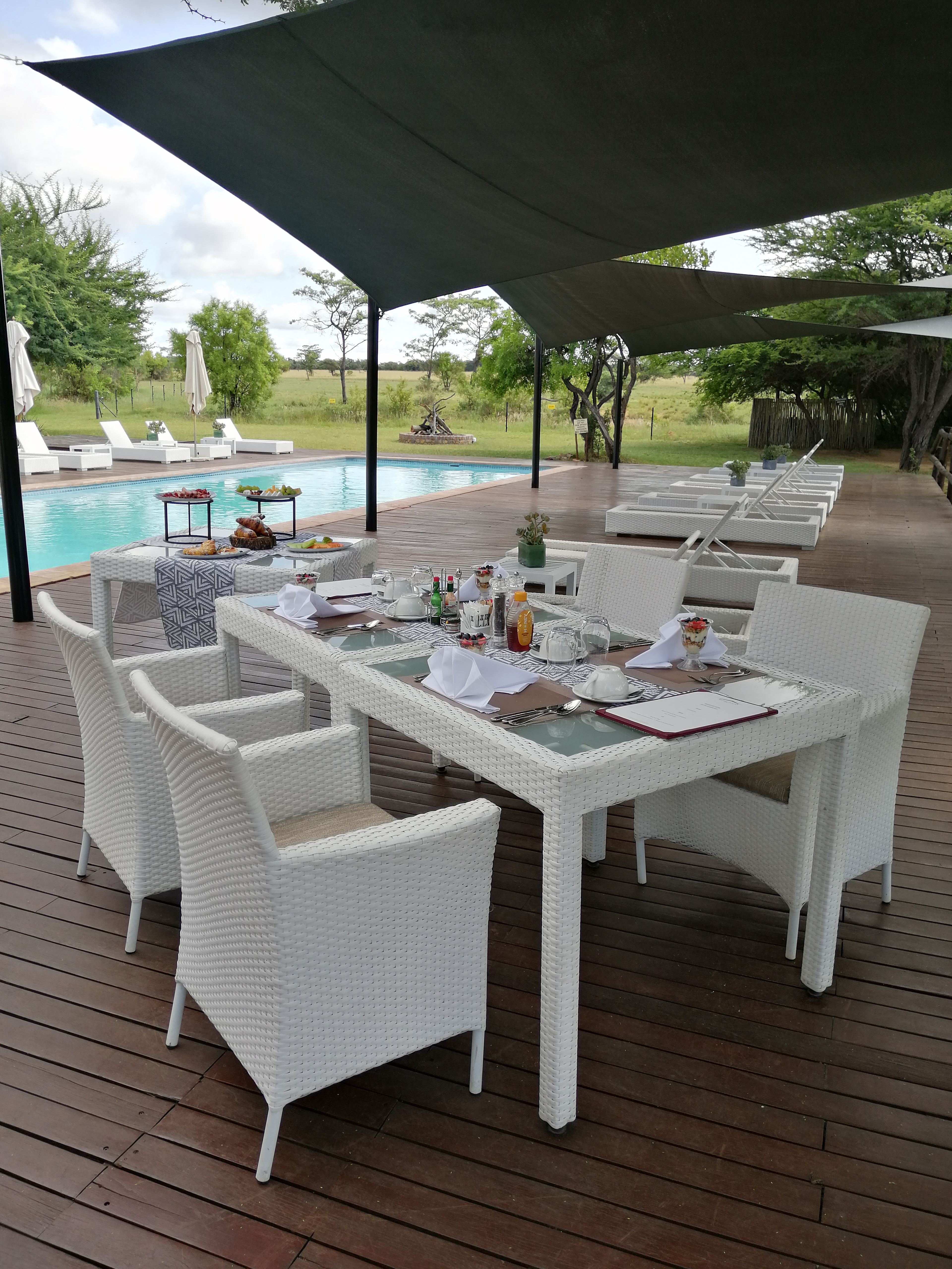 Außenterrasse mit Esstisch am Pool einer Luxus-Safari-Lodge in Südafrika