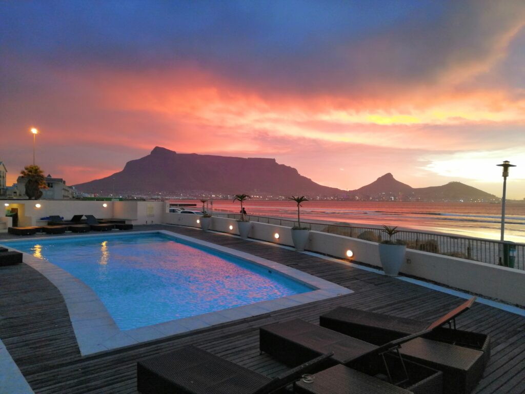 Traumblick auf den Tafelberg – vom Hotelpool direkt zum Sonnenuntergang

Ein atemberaubender Blick vom Pool deines Hotels am Strand: Im Hintergrund erhebt sich majestätisch der Tafelberg, während die Abendsonne den Himmel in warme Farben taucht. Der perfekte Ort, um den Tag entspannt ausklingen zu lassen – mit Blick auf eines der schönsten Wahrzeichen Südafrikas. Ideal für einen unvergesslichen Traumurlaub in Kapstadt.