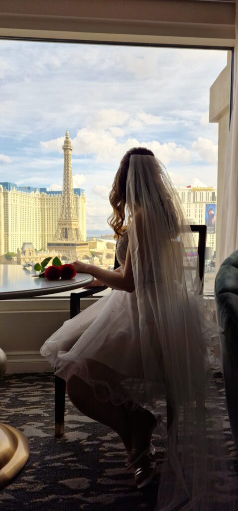 Larissa Wolfram-Kuhl im Brautkleid mit Frühstückstablett vor Hotelfenster mit Blick auf den Eiffelturm in Las Vegas, Vegas Bride