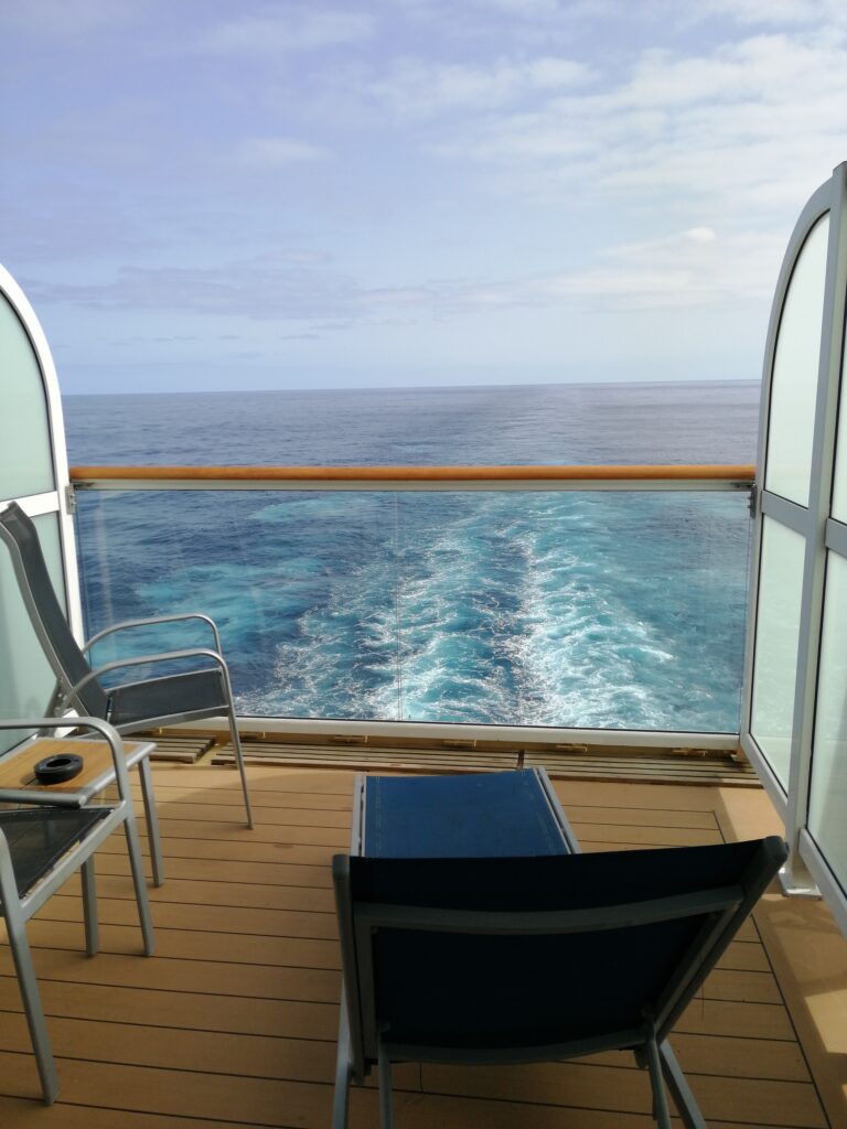 Privater Balkon mit Stuhl und Blick auf die Heckwelle eines Kreuzfahrtschiffs