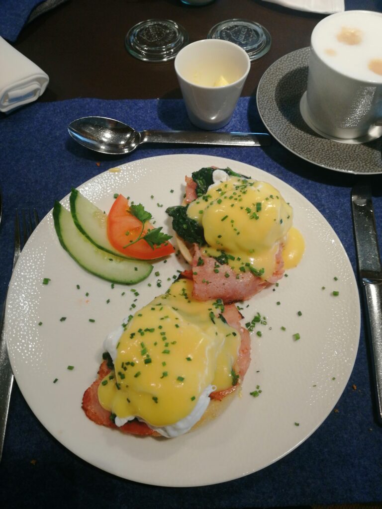 Eggs Benedict mit Lachs und Sauce Hollandaise beim Frühstück auf Kreuzfahrt