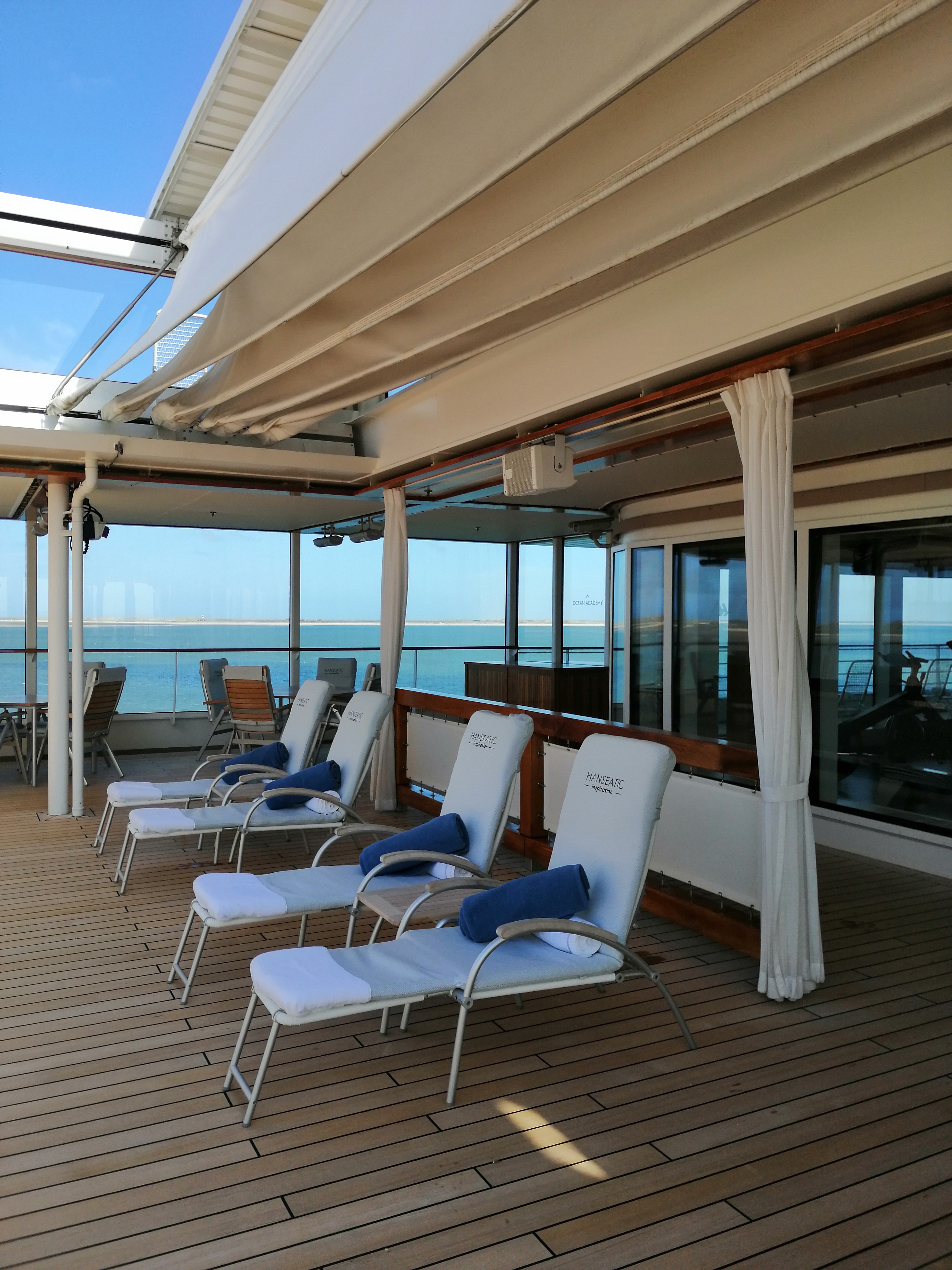 Überdachtes Sonnendeck mit Liegestühlen auf einem Kreuzfahrtschiff