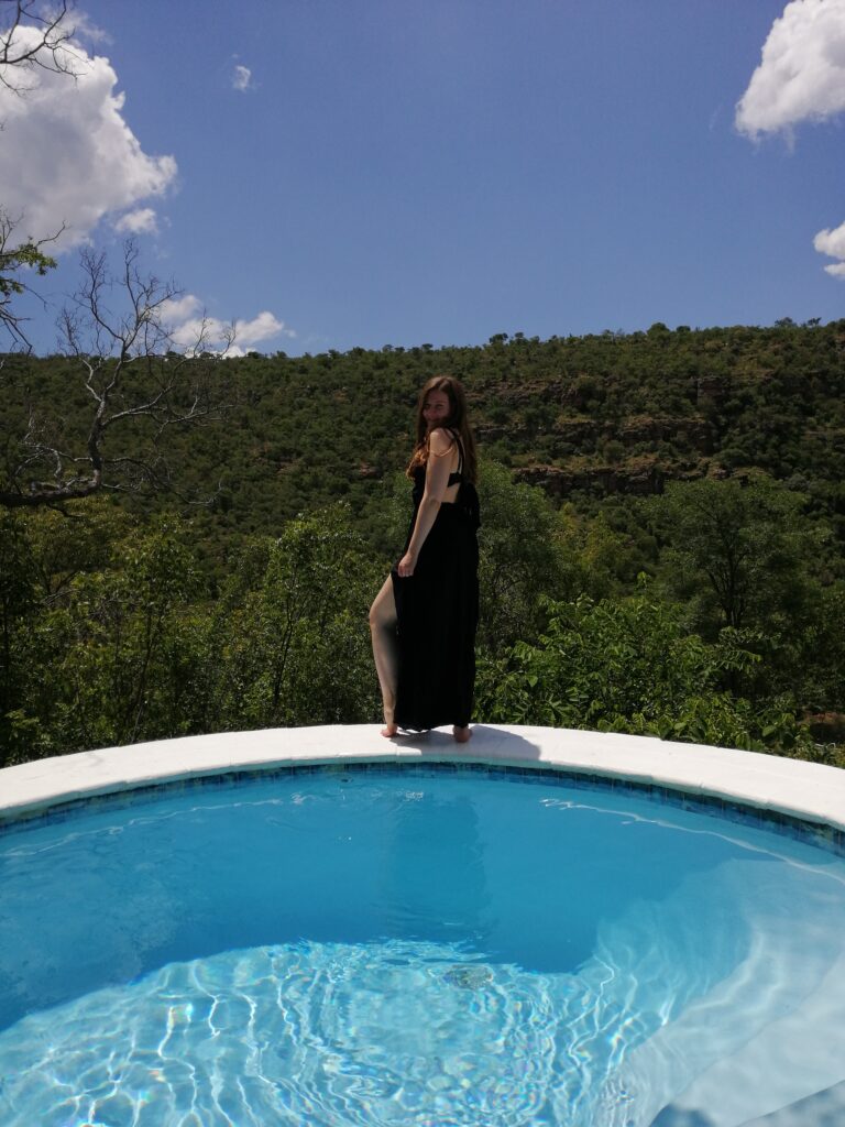 Frau am Rand eines Infinity-Pools mit Blick über die Landschaft Südafrikas