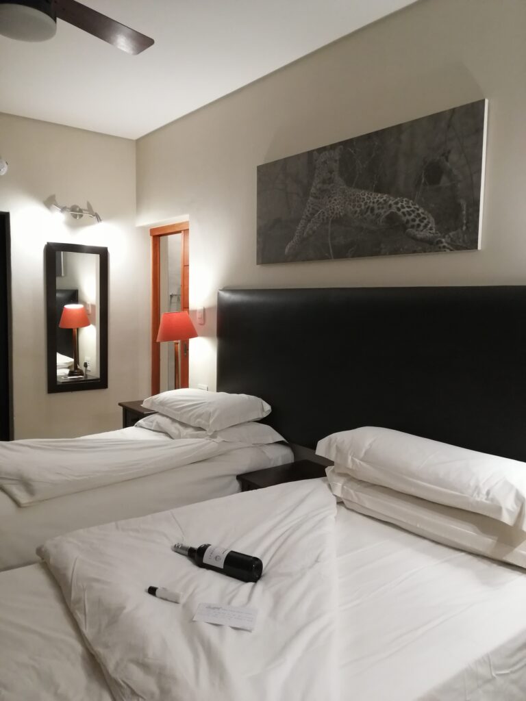 Zeitgemäße Safari-Suite mit zwei Betten und roten Nachttischlampen in Südafrika