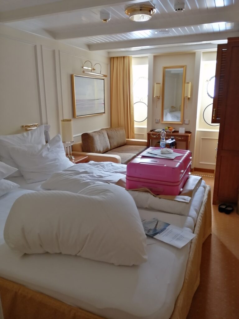 Hochwertige Kabine auf Kreuzfahrtschiff mit Bett und goldenen Elementen