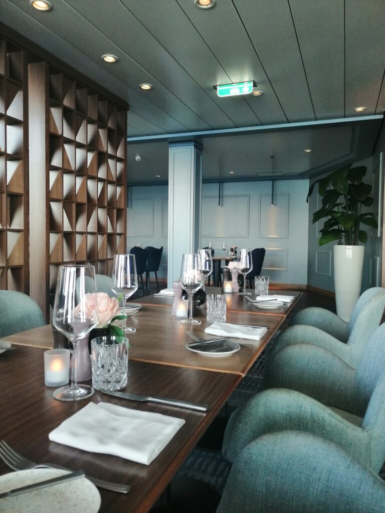 Schön gedeckte Restauranttische mit Stühlen und Pflanze im Hintergrund.