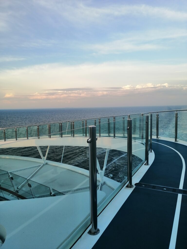 Designlaufstrecke auf Kreuzfahrtschiff mit Blick aufs Meer und Glasgeländer