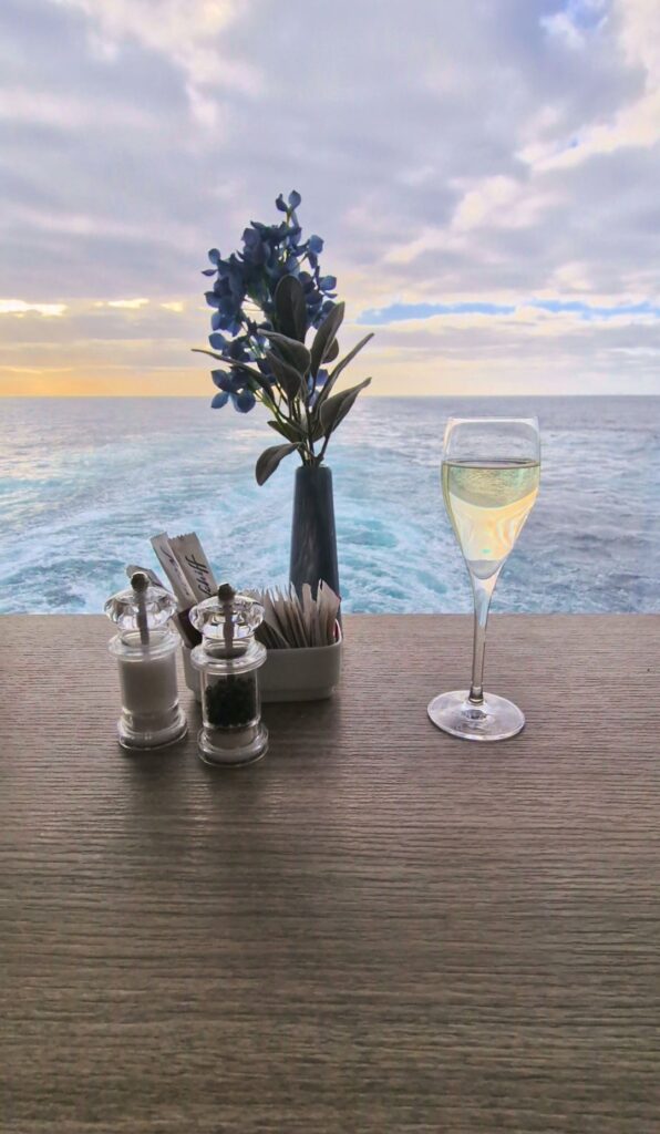 Sektglas auf Tisch mit Blumen und Meerblick