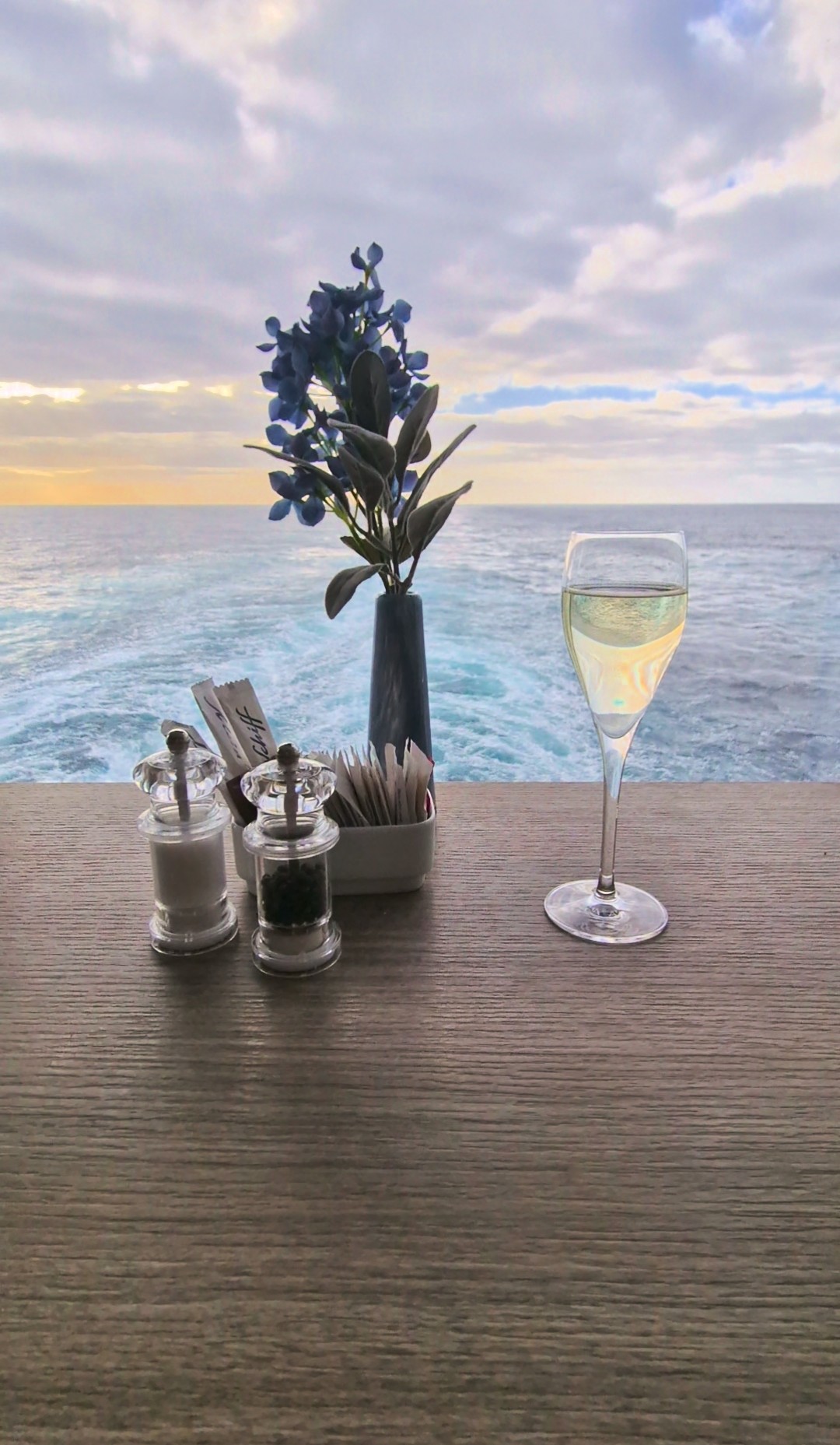 Sektglas auf Tisch mit Blumen und Meerblick